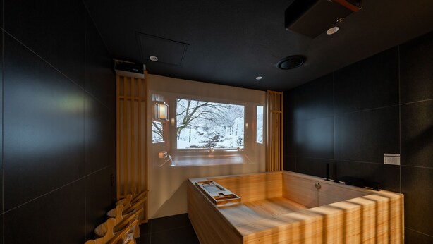 A modern bathroom with a wooden bathtub, a window with a snowy view, and a row of wooden benches. - Anook Ryokan Hotel Paju (Paju)