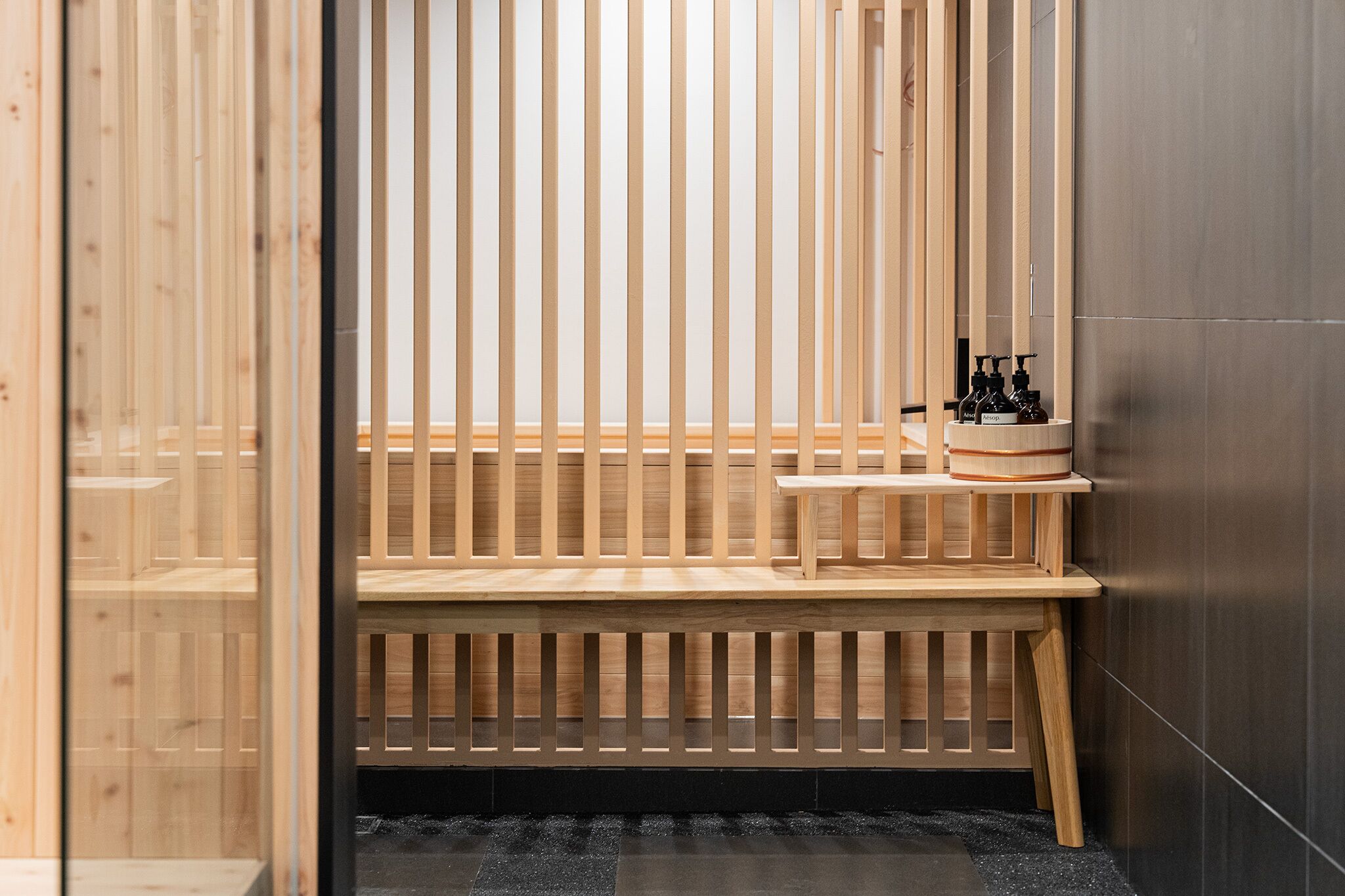Eine Holzsauna mit einer Bank und Regalen, auf denen Flaschen stehen.