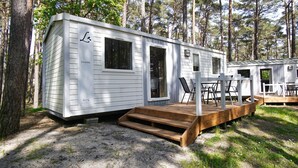 Una casa mobile con veranda e zona salotto all'aperto, immersa nel verde.