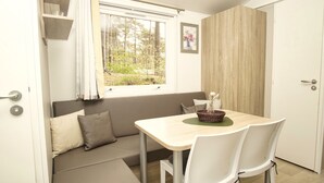 A compact room with a window, a sofa, a dining table with chairs, and a door.
