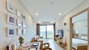 A modern hotel room with a dining area, a bed, a TV, and a balcony with a city view. - Thuy's Homestay - The Song Vung Tau (Ho Chi Minh City)