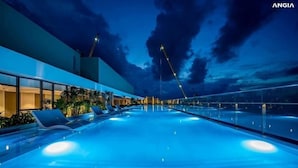 A large indoor swimming pool with lounge chairs and a modern building in the background. - Thuy's Homestay - The Song Vung Tau (Ho Chi Minh City)