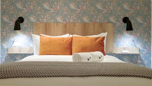 A bed with white and orange pillows, a rolled towel, and a woven rug. - w* | Amazing 1BR w/ Balcony  & AC in San Felipe (Panamá)