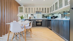 Eine moderne Küche mit weißen Schränken, einem eingebauten Backofen und einem Essbereich mit weißem Tisch und Stühlen.