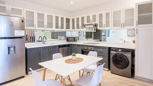 A modern kitchen with white cabinets, a stainless steel refrigerator, a microwave, a dishwasher, and a washing machine. - w* | Upgraded 1BR w/ Balcony in Panama (Panamá)