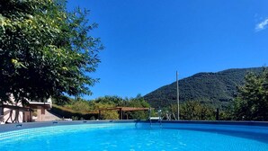 A clear blue swimming pool with a tiled edge, surrounded by greenery and a mountain in the background. - Residenza del Colle (Montelanico (Rome))