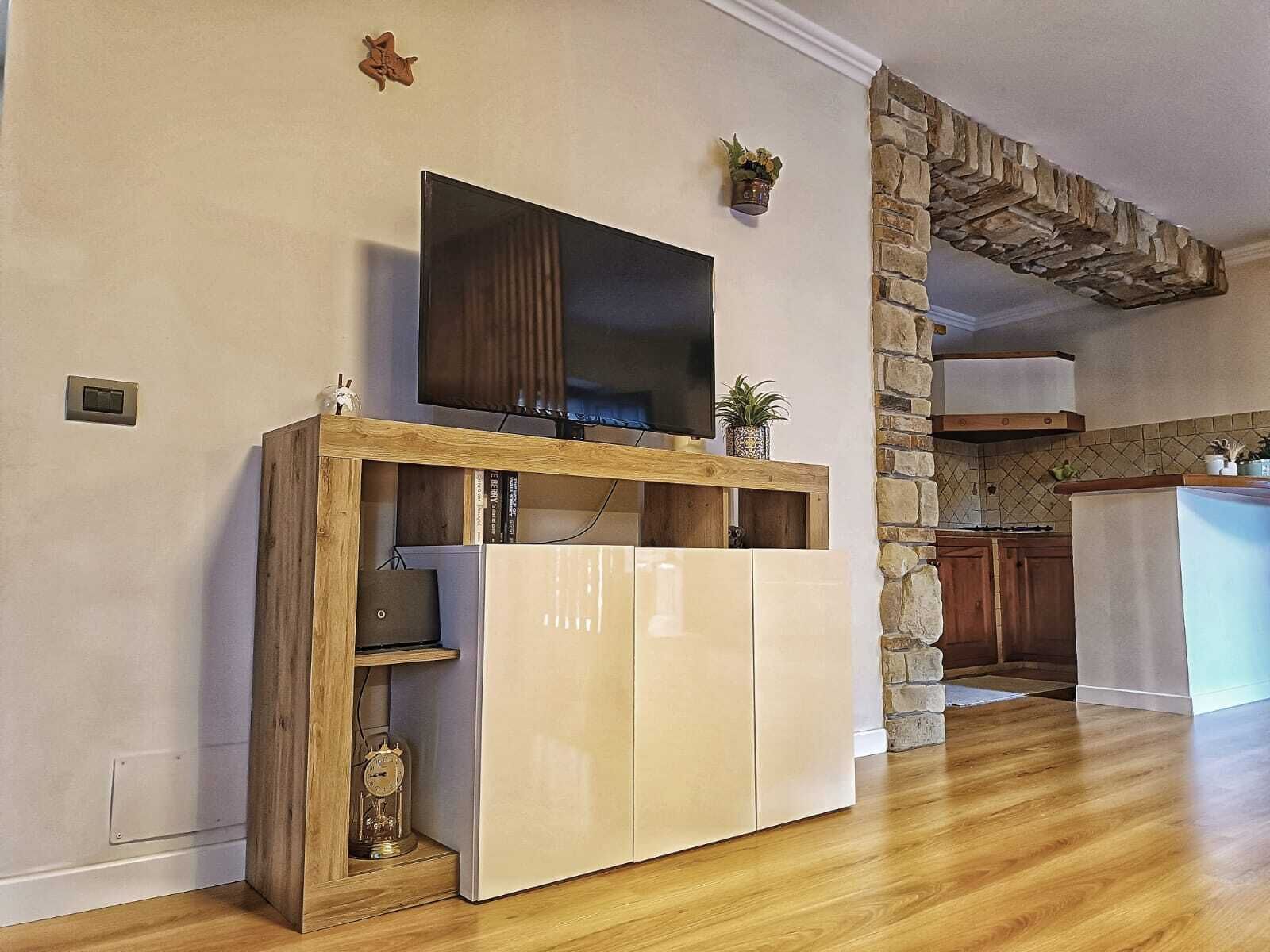 Una cocina moderna con una pared de acento de piedra, armarios de madera e incluso un televisor integrado.