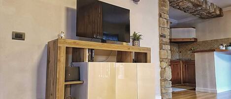Una cocina moderna con una pared de acento de piedra, armarios de madera e incluso un televisor integrado.