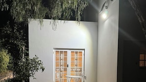 A courtyard with a white wall, a window with blinds, and two metal chairs. - Bordeaux 45 (Cape Town)