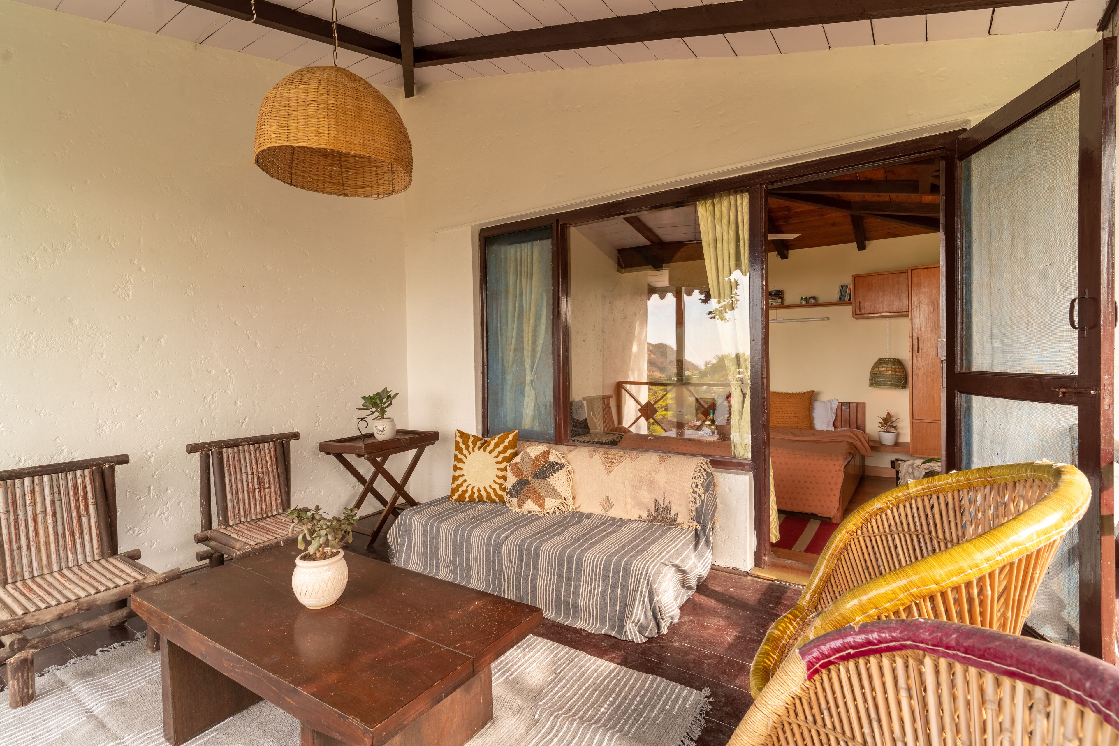 A cozy room with a wooden sofa, a dining table, and a wicker chair.