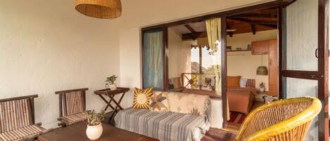 A cozy room with a wooden sofa, a dining table, and a wicker chair.