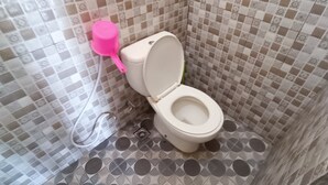 Ein Badezimmer mit Toilette, einem rosa Bidet und gemusterten Fliesen.
