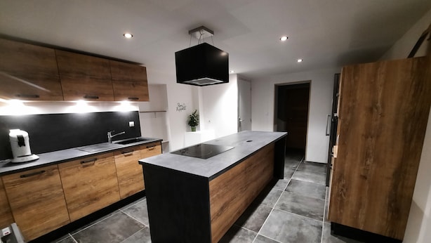 A modern kitchen with wooden cabinets, a black countertop, and a central island. - Chambre Économique Avec Salle de Bain Privative 1. Idéale Pour un Séjour Court ! (Vesoul)