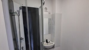 A modern bathroom with a glass-enclosed shower, a white sink, and a toilet. - Chambre Économique Avec Salle de Bain Privative 1. Idéale Pour un Séjour Court ! (Vesoul)