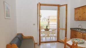 Une petite pièce agréable et chaleureuse, avec un canapé en bois, une table à manger entourée de chaises et un coin cuisine.