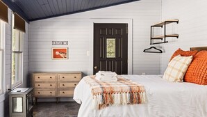 Un dormitorio con cama, cómoda y una puerta con ventanal.