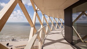 Un paseo marítimo en la playa con una terraza de madera y bancos, con vistas al mar.