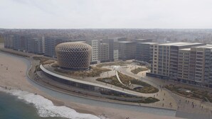Un edificio moderno con un diseño esférico único, rodeado de zonas ajardinadas y edificios residenciales colindantes.