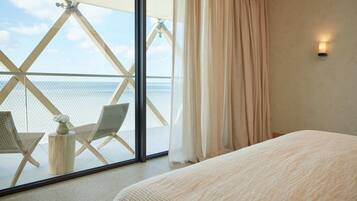 A hotel room with a large window, a bed, and a small table with a vase.