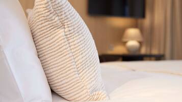 A bed with white bedding and striped pillows.