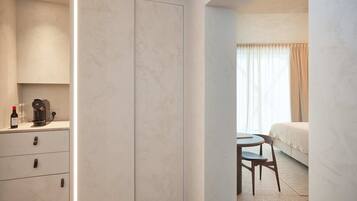 Een hotelkamer met een bed, een klein tafeltje met stoel, een minibars kast.