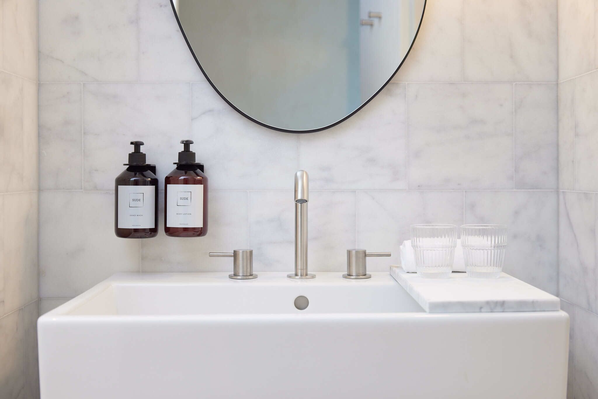 A bathroom with a white sink, two bottles of hand soap, and a mirror.
