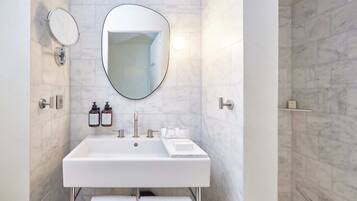 A modern bathroom with a white sink, two mirrors, and a large mirror above the sink.