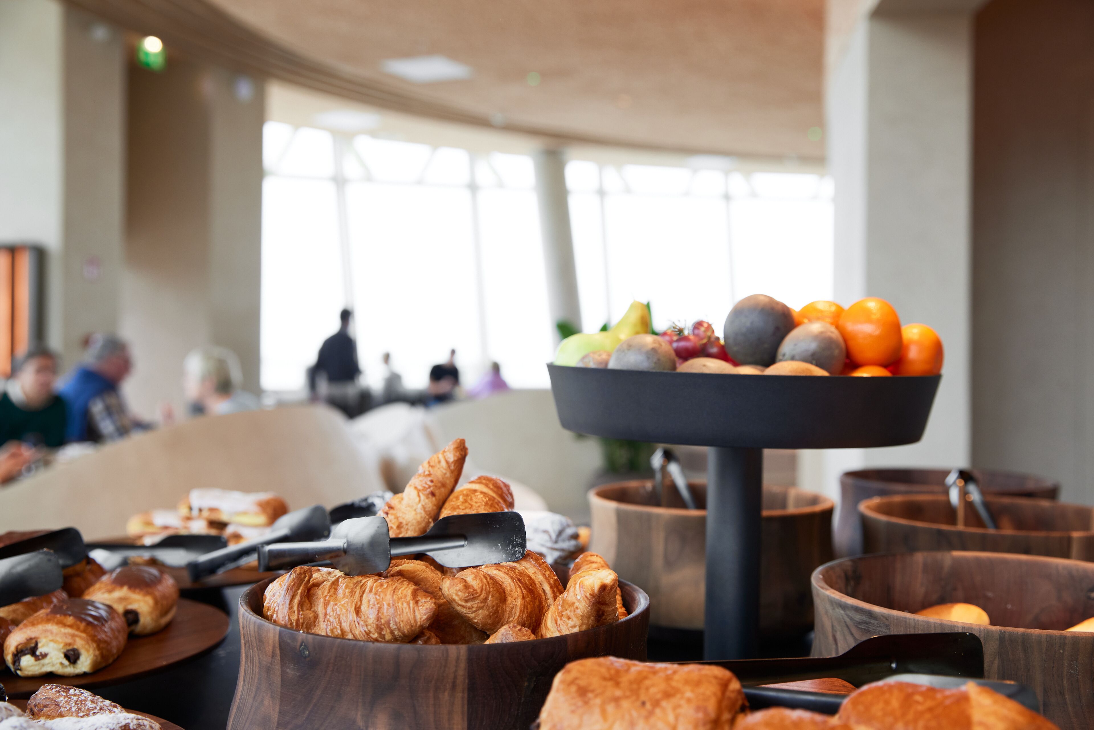 A breakfast buffet with croissants, fruits, and oranges.