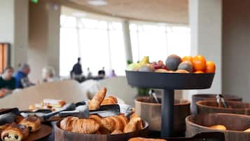 A breakfast buffet with croissants, fruits, and oranges.
