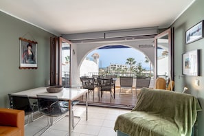Enjoy a coastal view from the comfort of this stylish living space, featuring a dining area, sofa, and patio with outdoor seating.