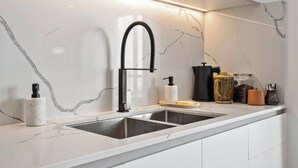 A modern kitchen with a sleek black faucet, marble backsplash, and a stainless steel sink. - Cityscape at The Elliott in the Heart of Hobart (Hobart)