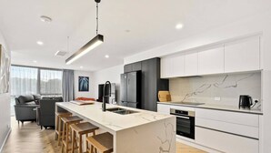 Una cocina moderna con encimera de mármol, electrodomésticos de acero inoxidable y una barra con taburetes.
