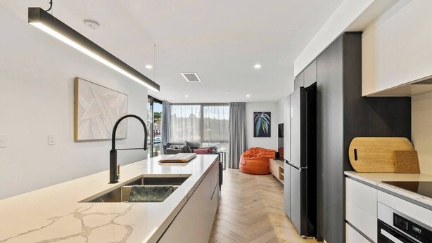 Una cocina moderna con encimera de mármol, pileta integrada y tabla de madera cortada a la derecha.