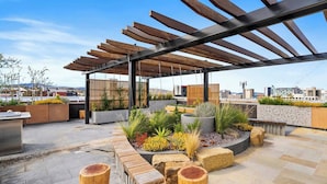 Un jardín en la azotea con pérgola de madera, macetas y zonas de estar.