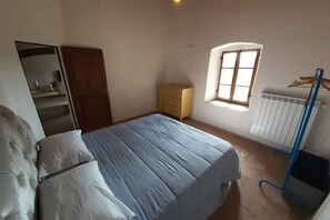 Une chambre à coucher avec un lit, une armoire, un radiateur et une fenêtre.