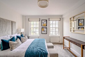 Ein Schlafzimmer mit Bett, Nachttischen, einem Schreibtisch und Bildern an den Wänden.