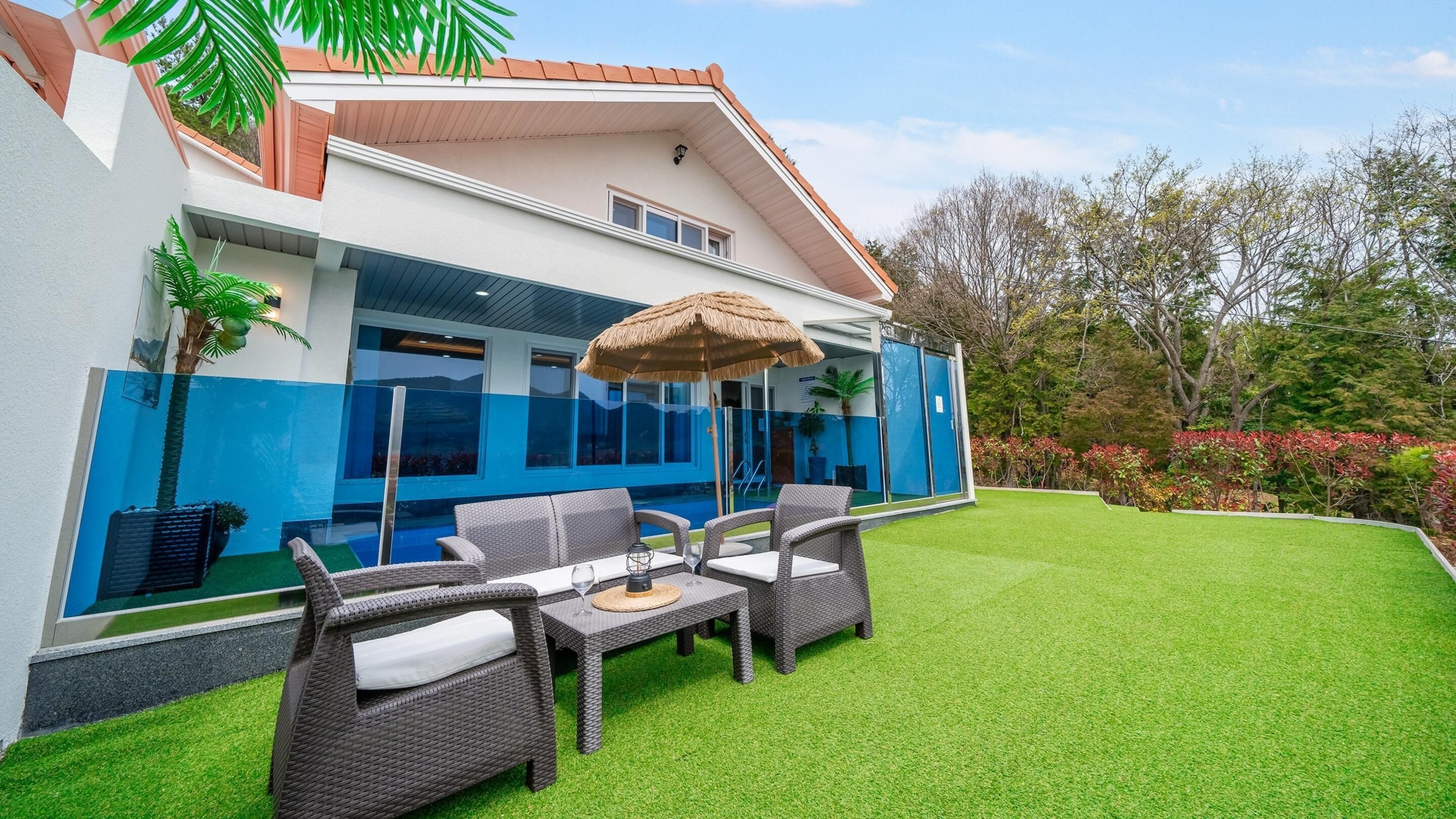 A modern house with a pool, outdoor furniture, and a well-maintained lawn.
