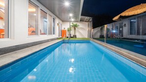 A swimming pool with clear blue water, surrounded by a white exterior wall with large windows. - Namhae Eagless Poolvilla Pension (Namhae)
