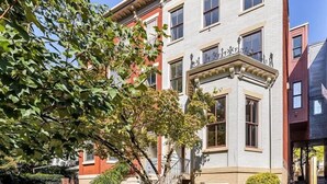 Un edificio de varios pisos con entrada en esquina, ventanas grandes y un balcón visible.