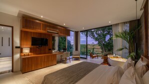 Une chambre moderne avec un grand lit, un bureau en bois, une télévision et une vue sur l’extérieur.