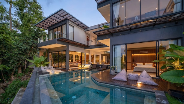 Une maison moderne à deux étages, dotée d’une piscine, de grandes fenêtres et d’un jardin bien entretenu.