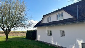 Et hvidt hus med skråtag og to vinduer.