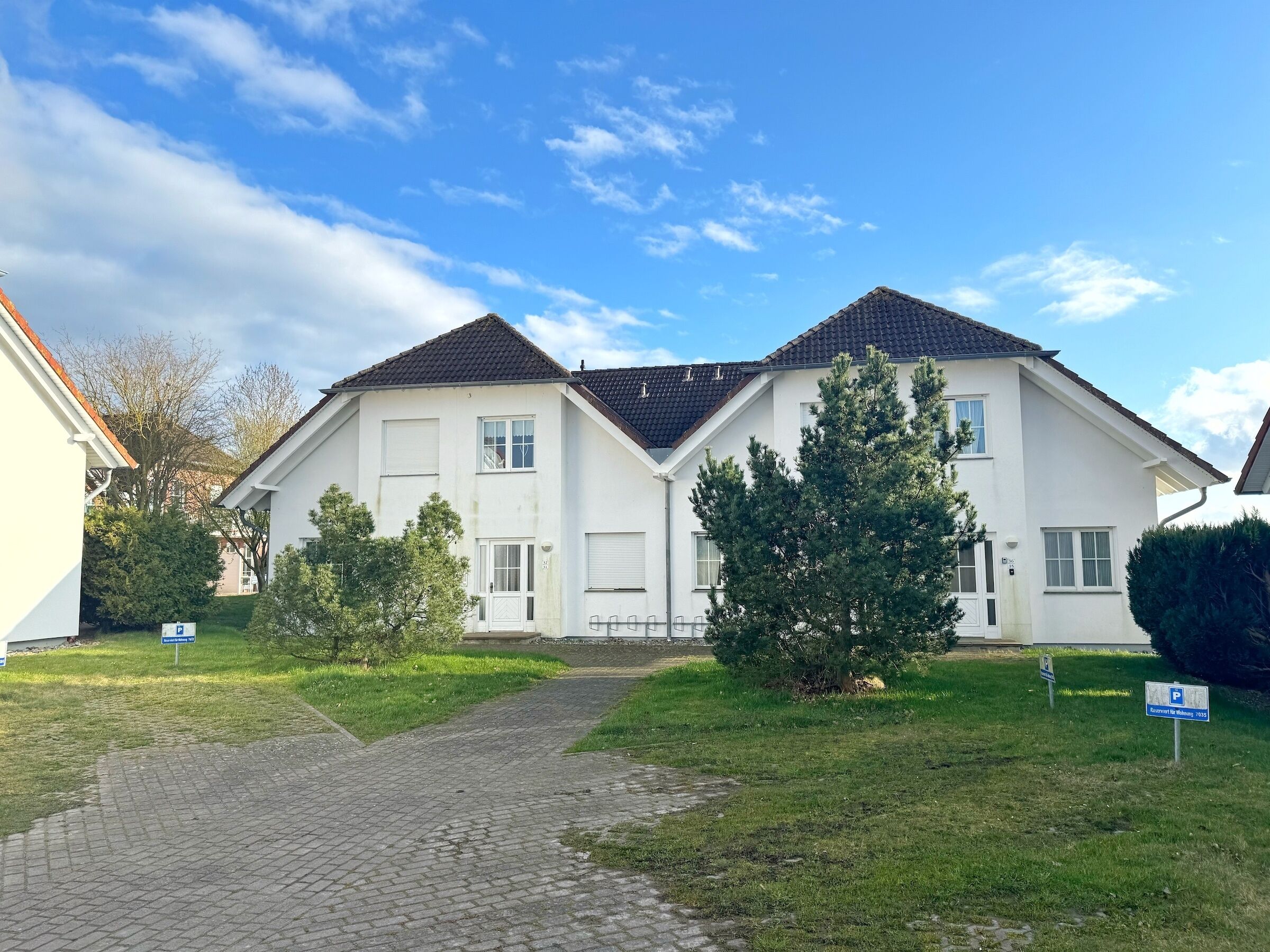 Ein zweistöckiges Wohnhaus mit befestigter Auffahrt und einer kleinen Rasenfläche.