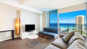 Een moderne hotelkamer met een groot balkon, een flatscreen televisie, een bank en een kleine tafel.