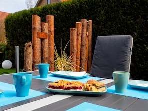 Enjoy a meal al fresco in this charming outdoor dining area, complete with a table set for two and a comfortable chair.