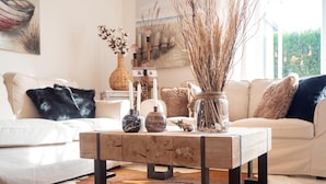 Una sala de estar moderna con una mesa de centro de madera, jarrones decorativos y un tapete de cuero de vaca.