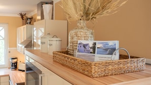 Una encimera de cocina con una cesta trenzada que contiene un jarrón con plantas secas y un folleto.