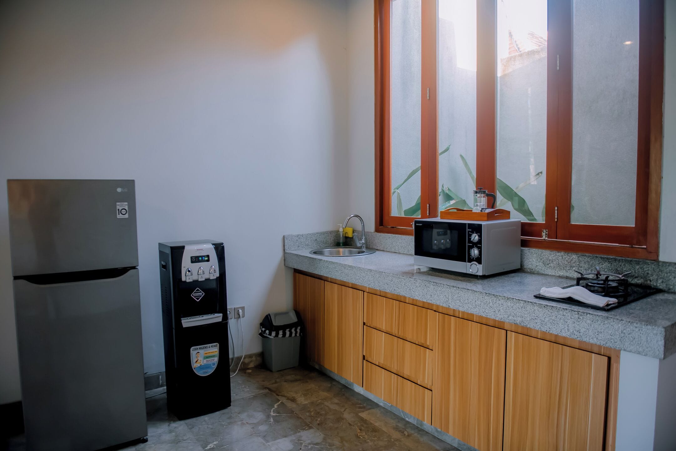 A compact kitchen with a refrigerator, microwave, sink, and a small trash bin.