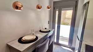 A modern dining area with a long table, two chairs, and pendant lighting.