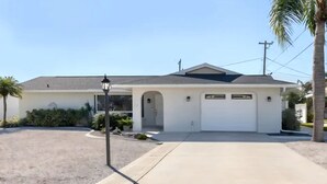 A single-story house with a garage, a driveway, and a small garden area.